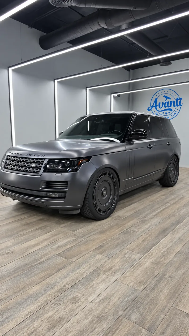 Satin gray Range Rover with tinted windows in the lit bay at Avanti Window Tint