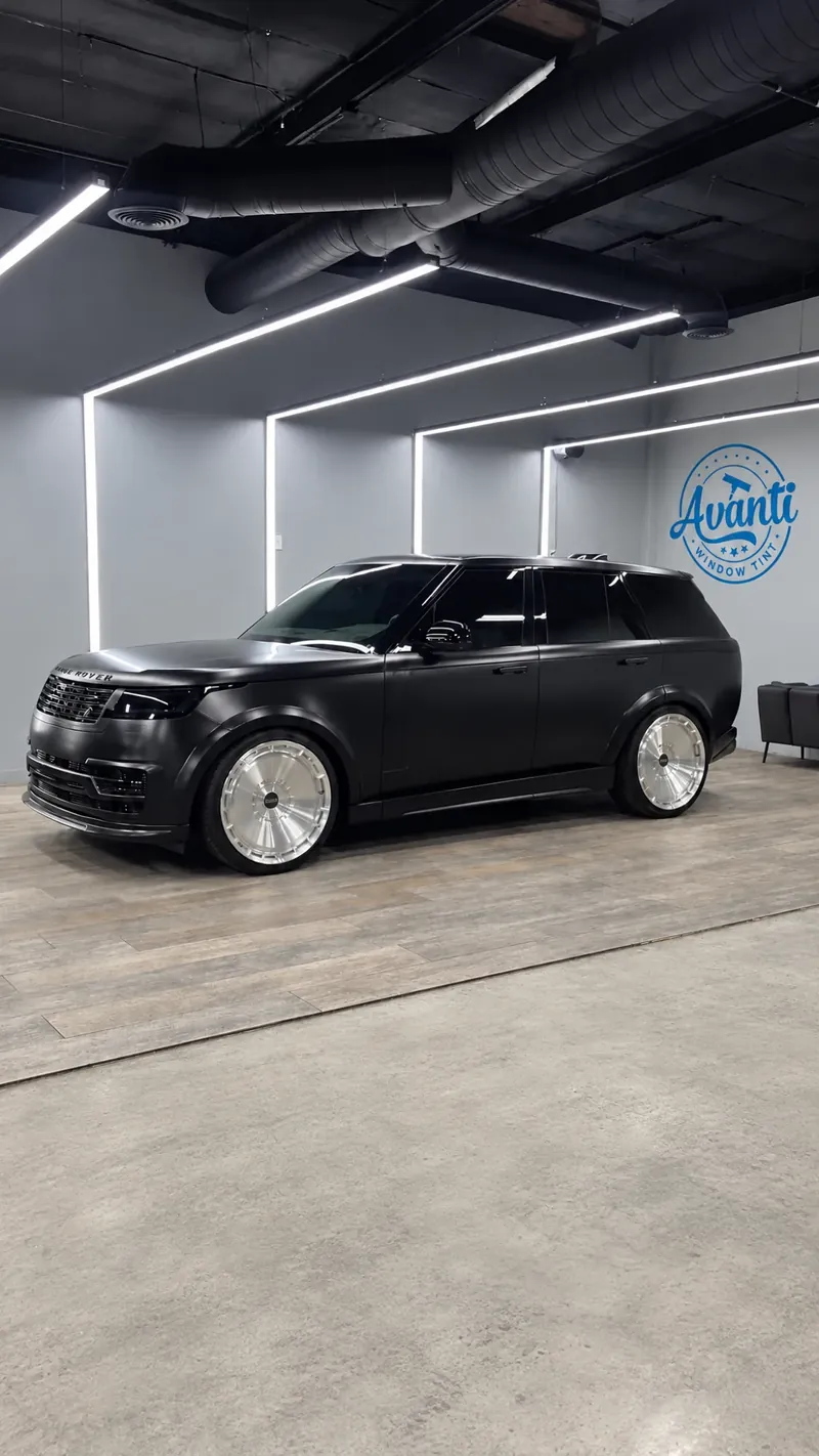 Matte black Range Rover seen from the side in the lit bay at Avanti Window Tint